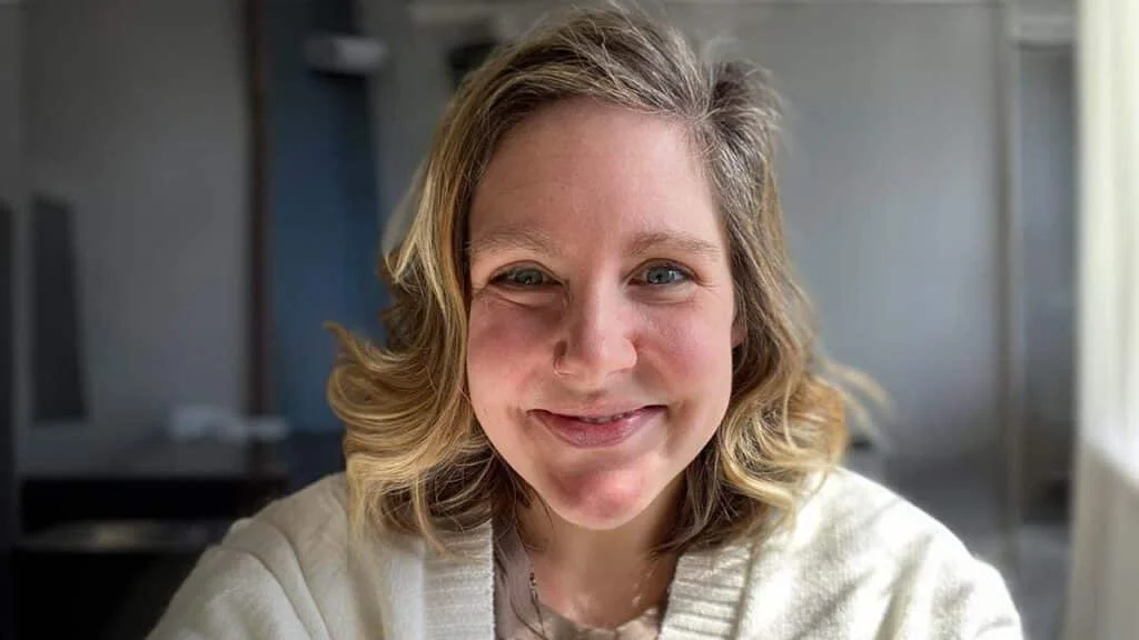 headshot of blonde lady in a grey neutral, dim room