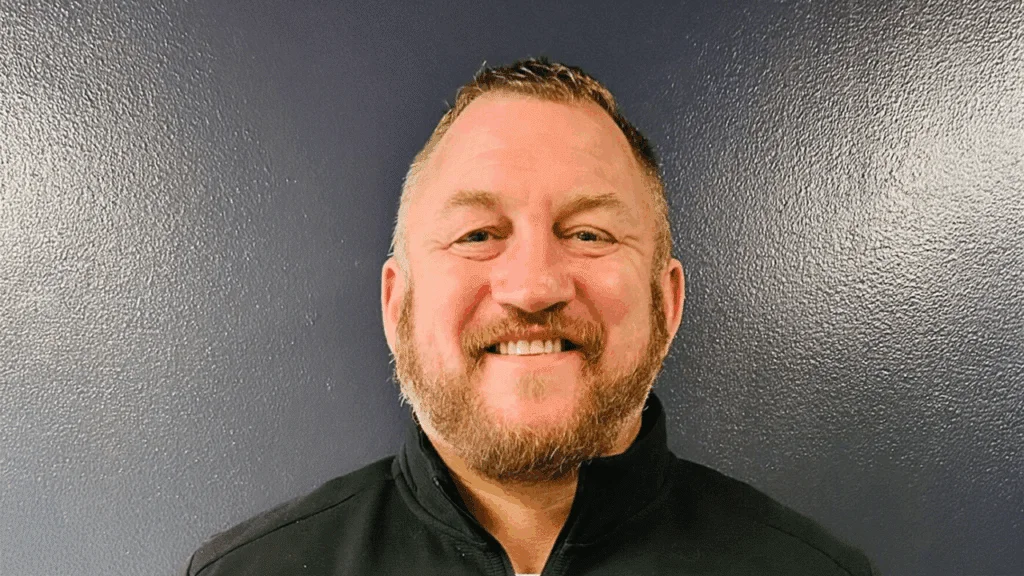 Headshot of Chad Winfrey. White male with clean cut handle bar mustache and beard, and black collard shirt
